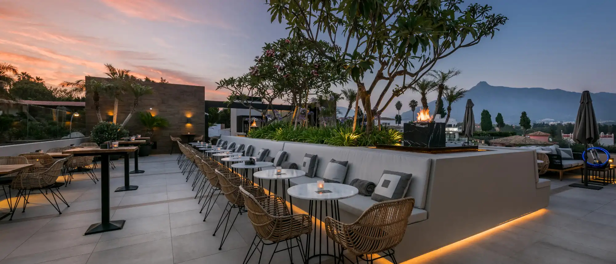 The contemporary rooftop terrace of Air by BREATHE in Nueva Andalucia, showing sleek water features, vertical gardens, and panoramic views of La Concha mountain