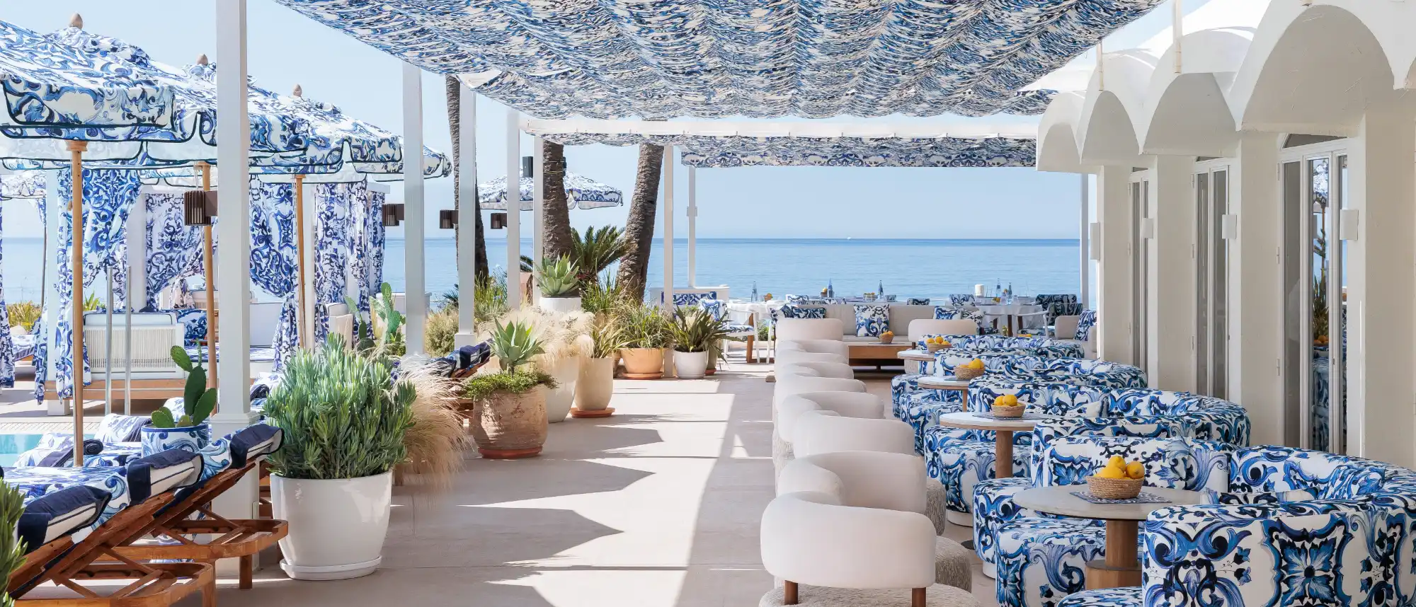 The stylish beachfront pool deck of La Cabane by Dolce and Gabbana in Marbella, featuring luxury Balinese beds and iconic high-fashion designer detailing